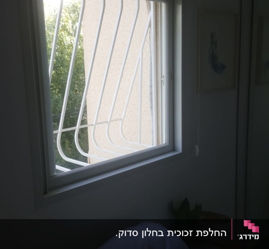 חלון זכוכית עם סורגי מתכת לבנים